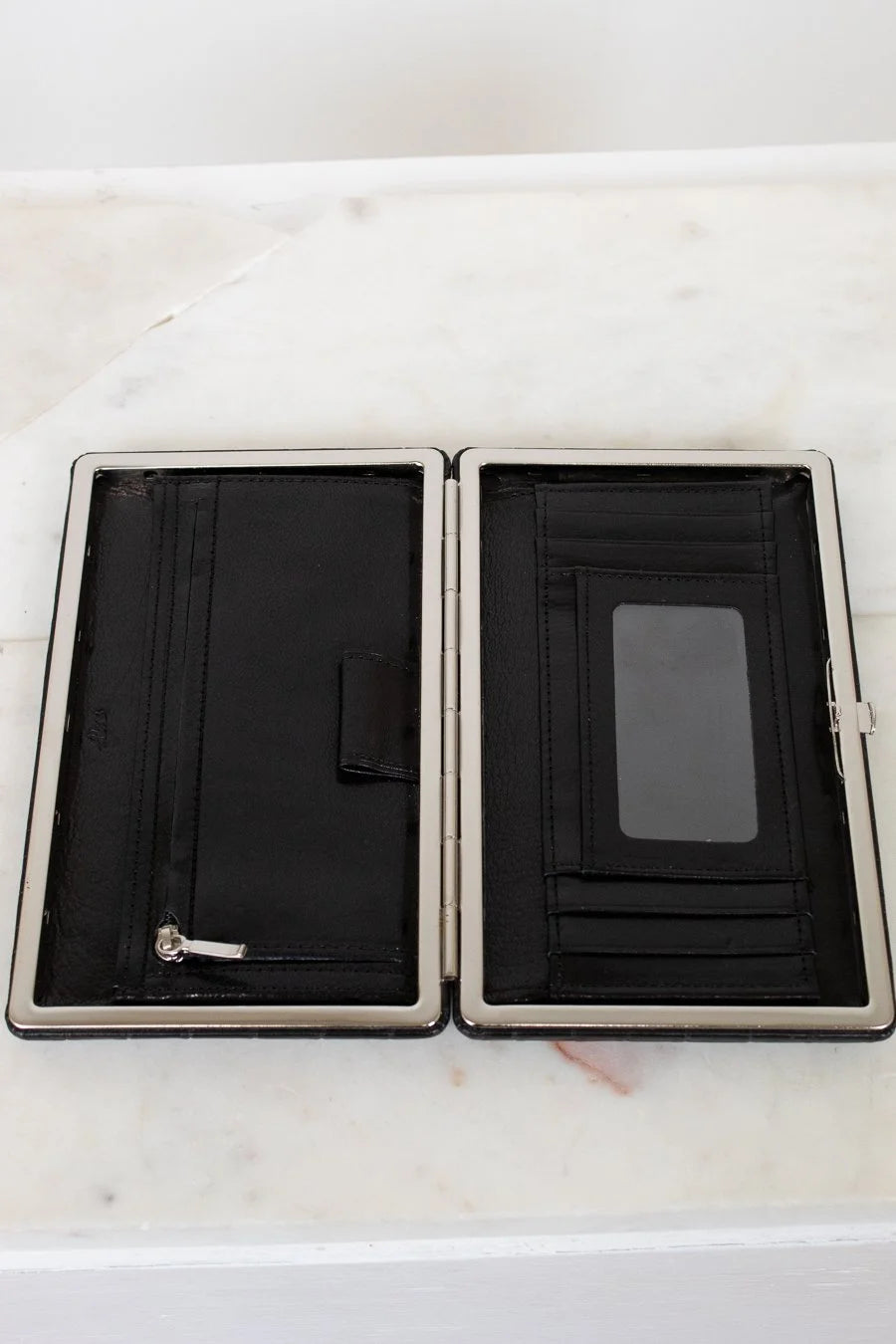 Black wallet with silver trim on a white marble surface