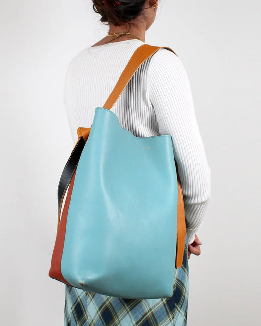 Person wearing a blue and brown tote bag on a plain background