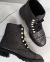 Metallic textured boots with pearl embellishments on a light wooden floor.