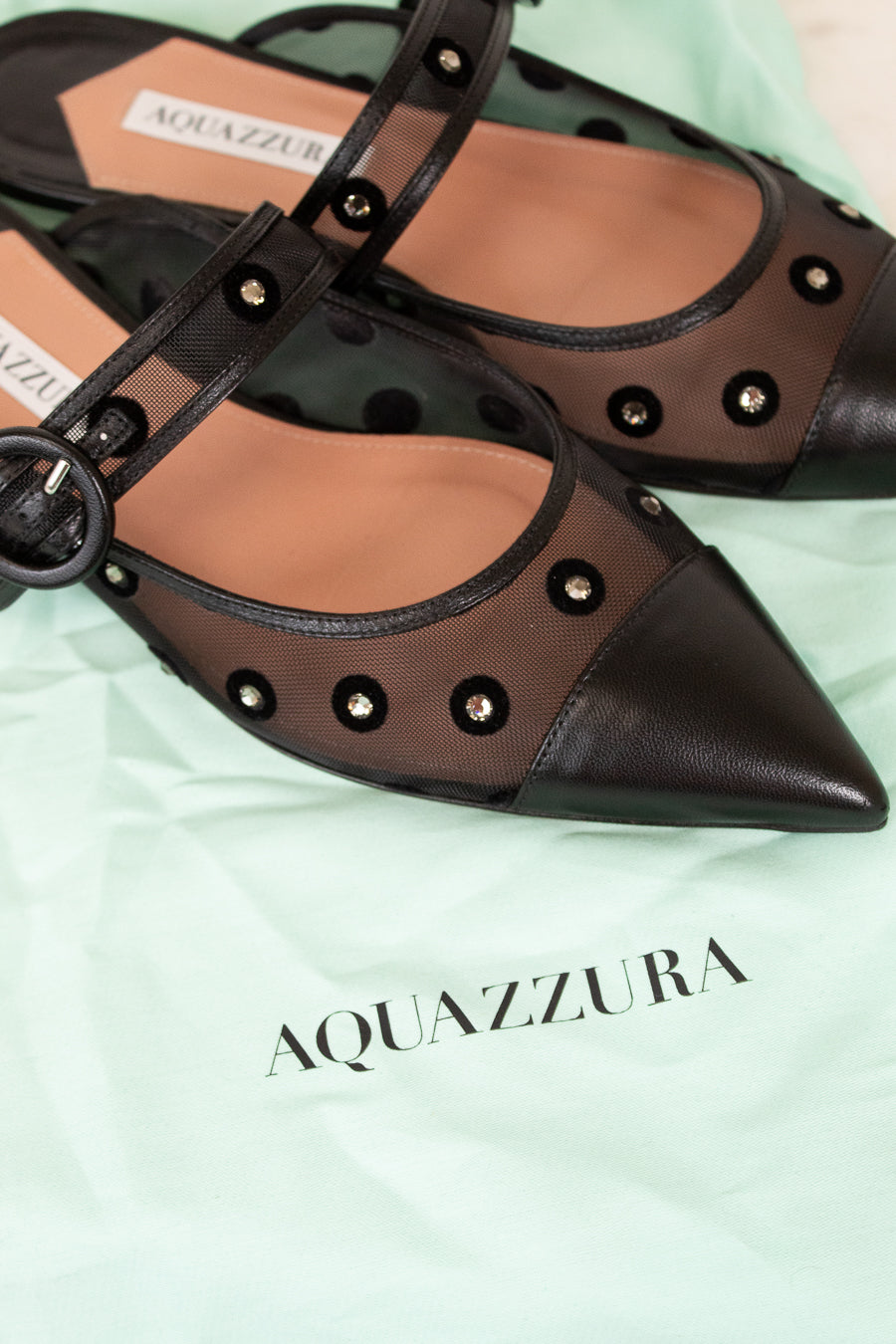Pair of Aquazzura shoes on a light green background