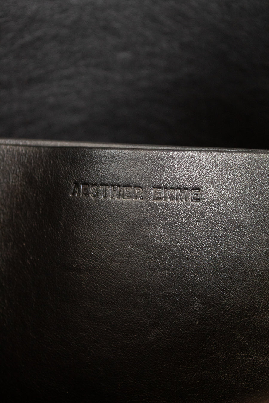Close-up of a dark brown leather purse with branding.