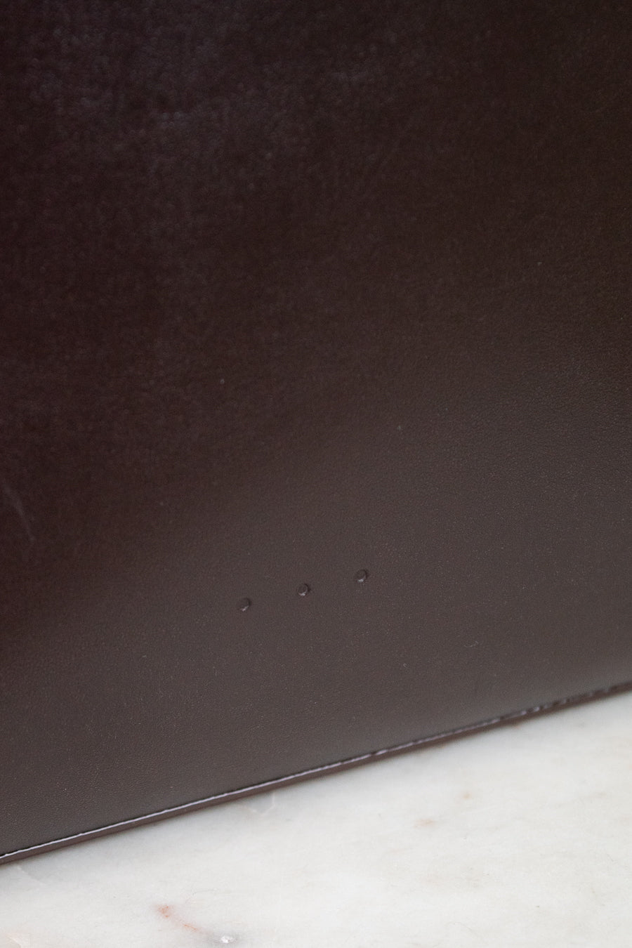 Close-up of a dark brown leather surface on a marble background