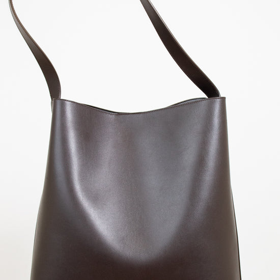 Dark brown leather handbag with a shoulder strap on a white background