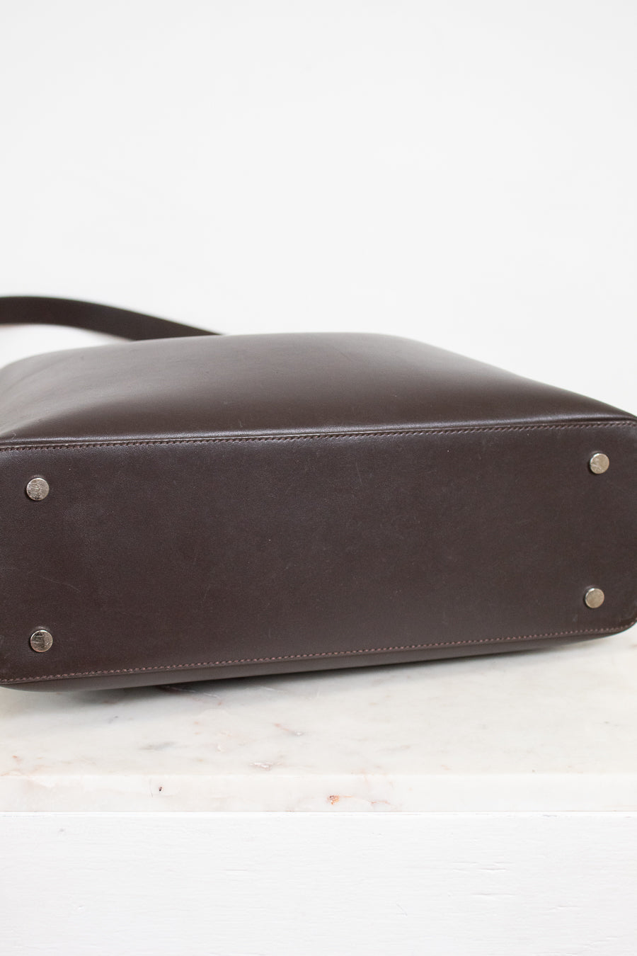 Brown leather handbag with silver studs on a white background