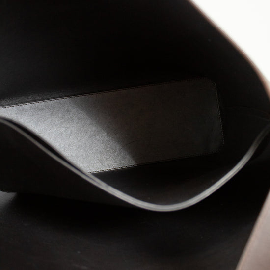 Close-up of a dark brown leather bag with a visible brand logo.