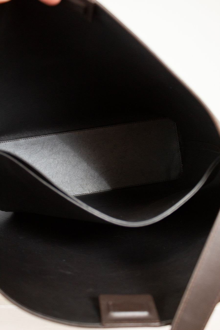 Close-up of a dark brown leather bag with a visible brand logo.