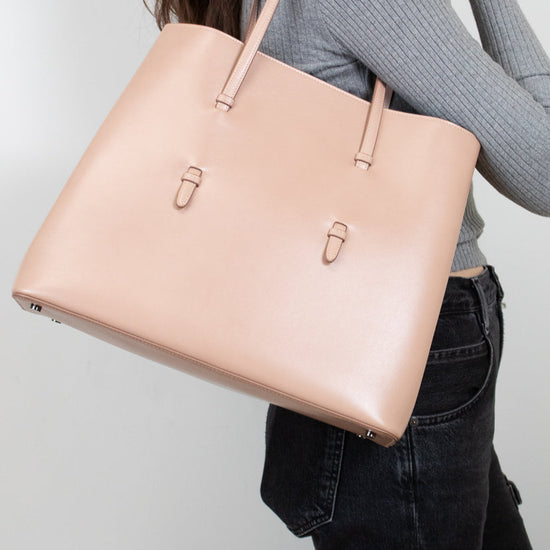 Person holding a beige tote bag against a plain background