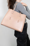 Person holding a beige tote bag against a plain background
