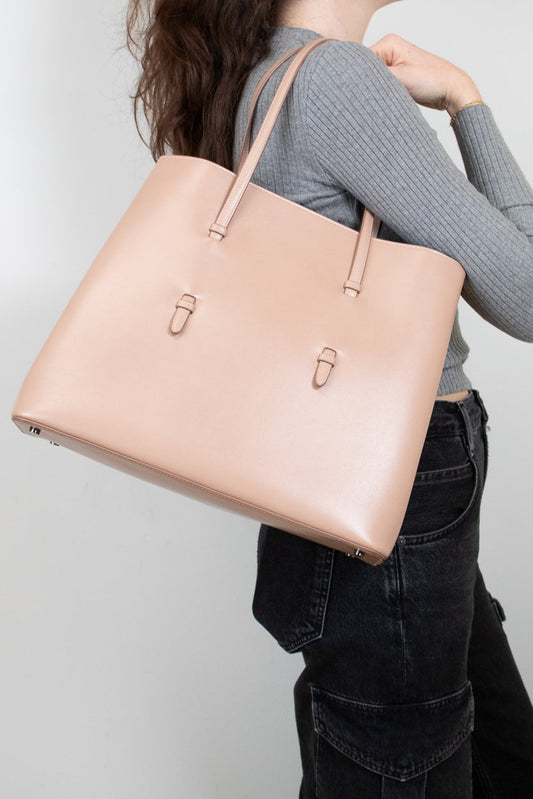 Person holding a beige tote bag against a plain background