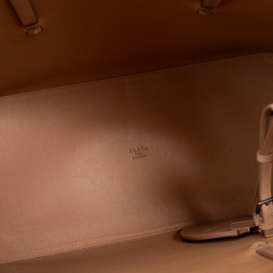 Close-up of a brown leather bag with visible stitching and a brand logo.
