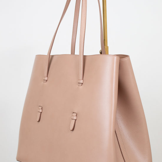 Side angle of beige leather tote purse on white background