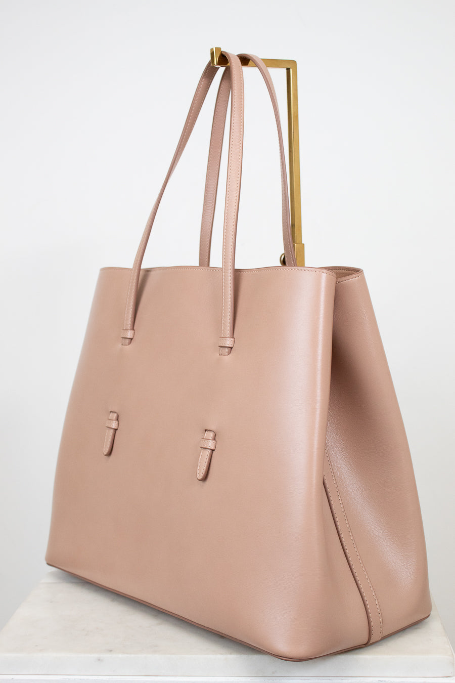 Side angle of beige leather tote purse on white background