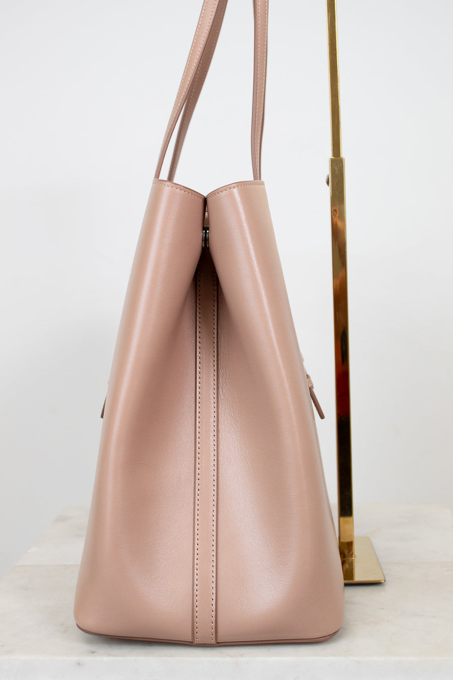 Side angle of beige leather tote on white background