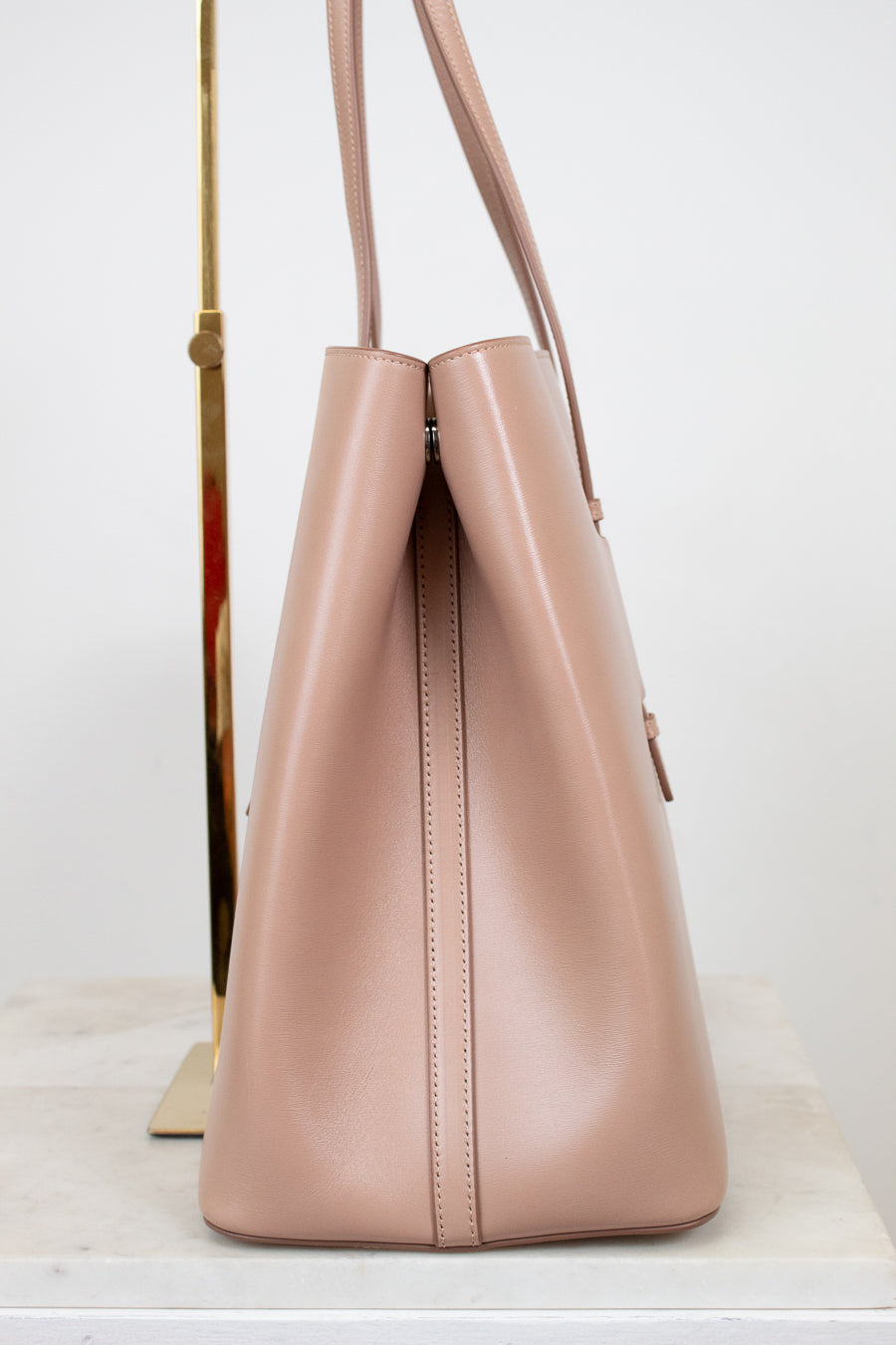 Side angle of beige leather tote on white background