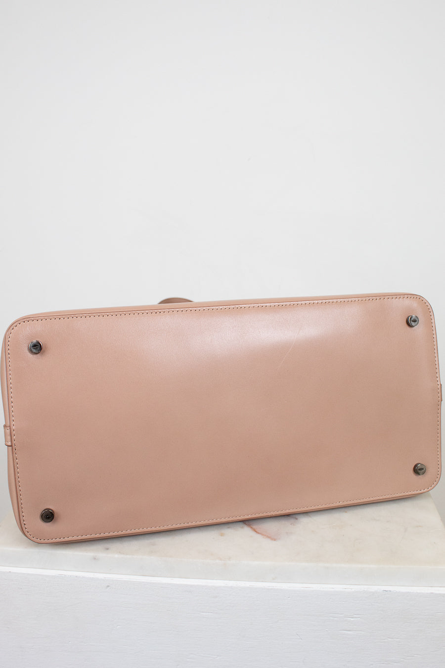 Base of beige handbag on a white background