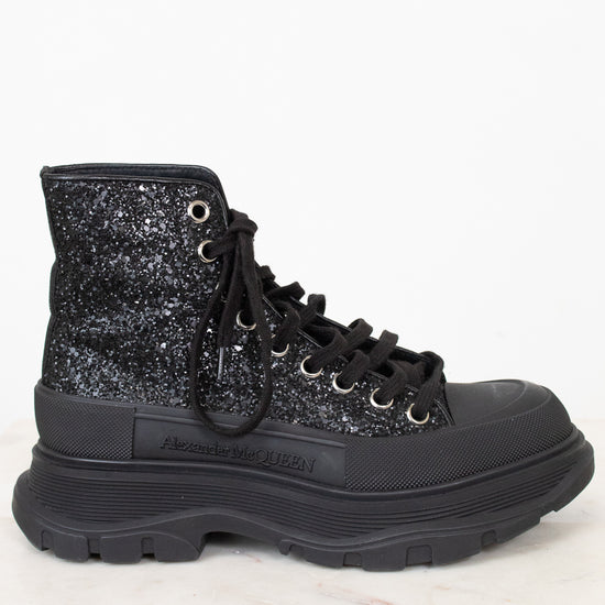 A black high-top lace-up boot with a glittery black and silver upper, black laces, and a chunky black sole, shown against a white background.
