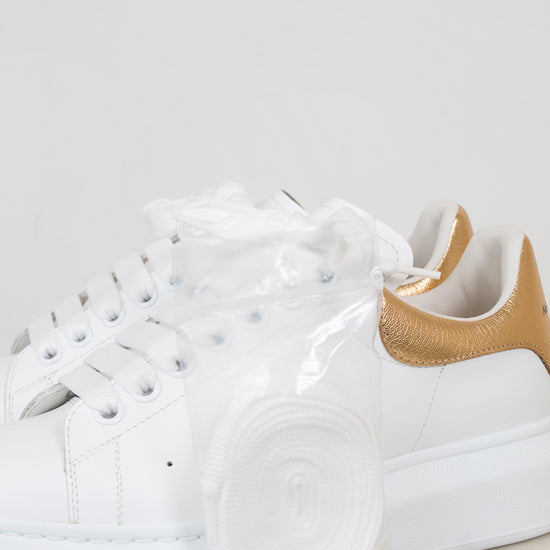 White sneakers with gold accents on a light gray background