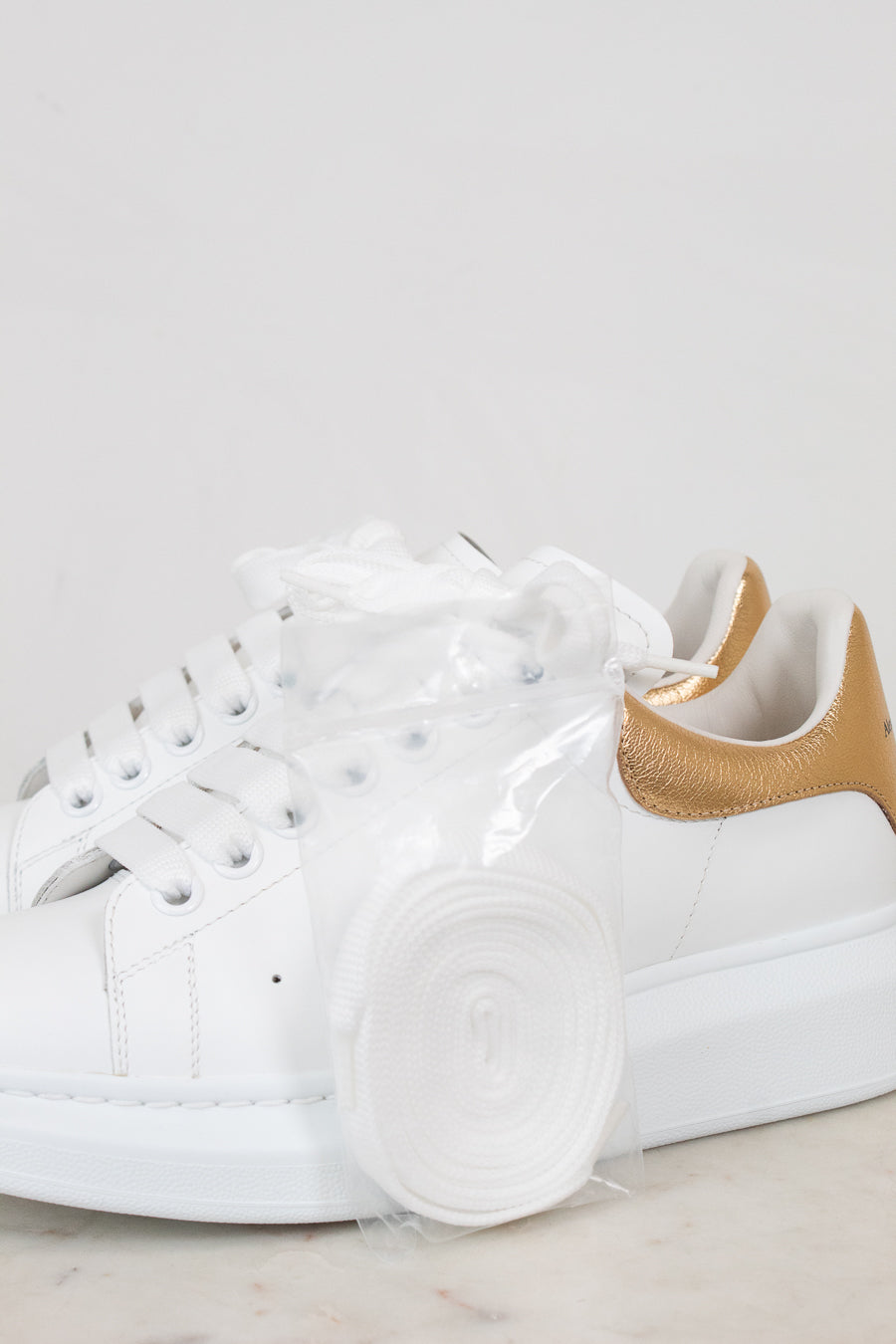 White sneakers with gold accents on a light gray background