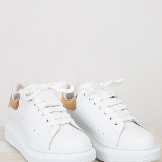 White sneakers with tan accents on a light gray background
