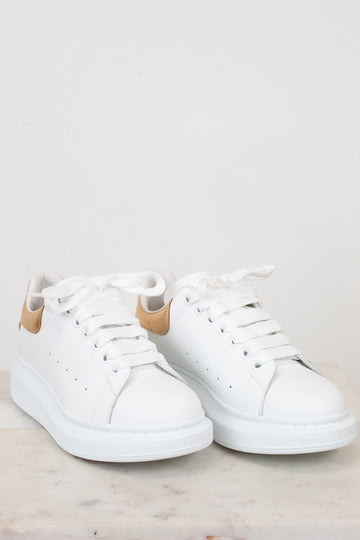 White sneakers with tan accents on a light gray background