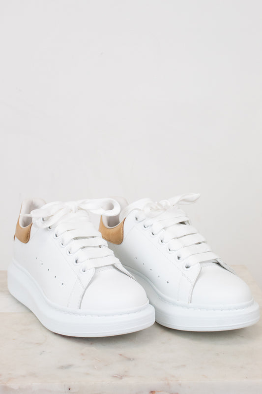 White sneakers with tan accents on a light gray background