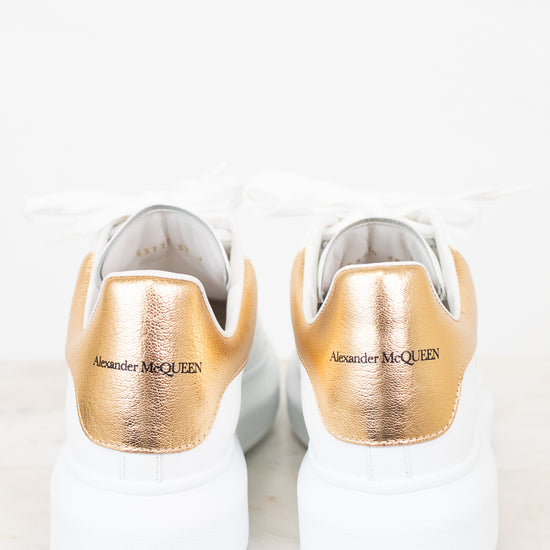White sneakers with gold soles and 'Alexander McQueen' branding on a white background