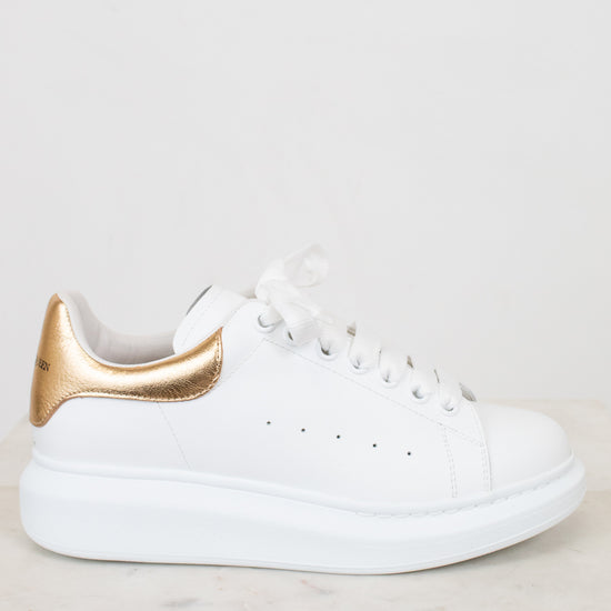 White sneaker with gold accents on a light background