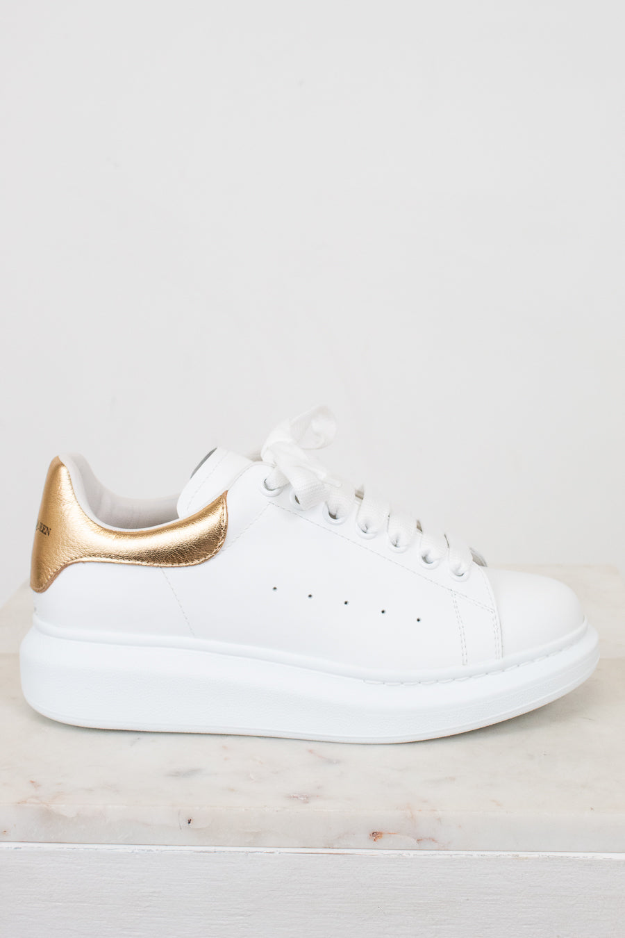White sneaker with gold accents on a light background