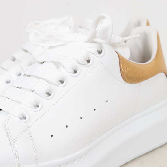 White sneaker with a gold accent on a light background