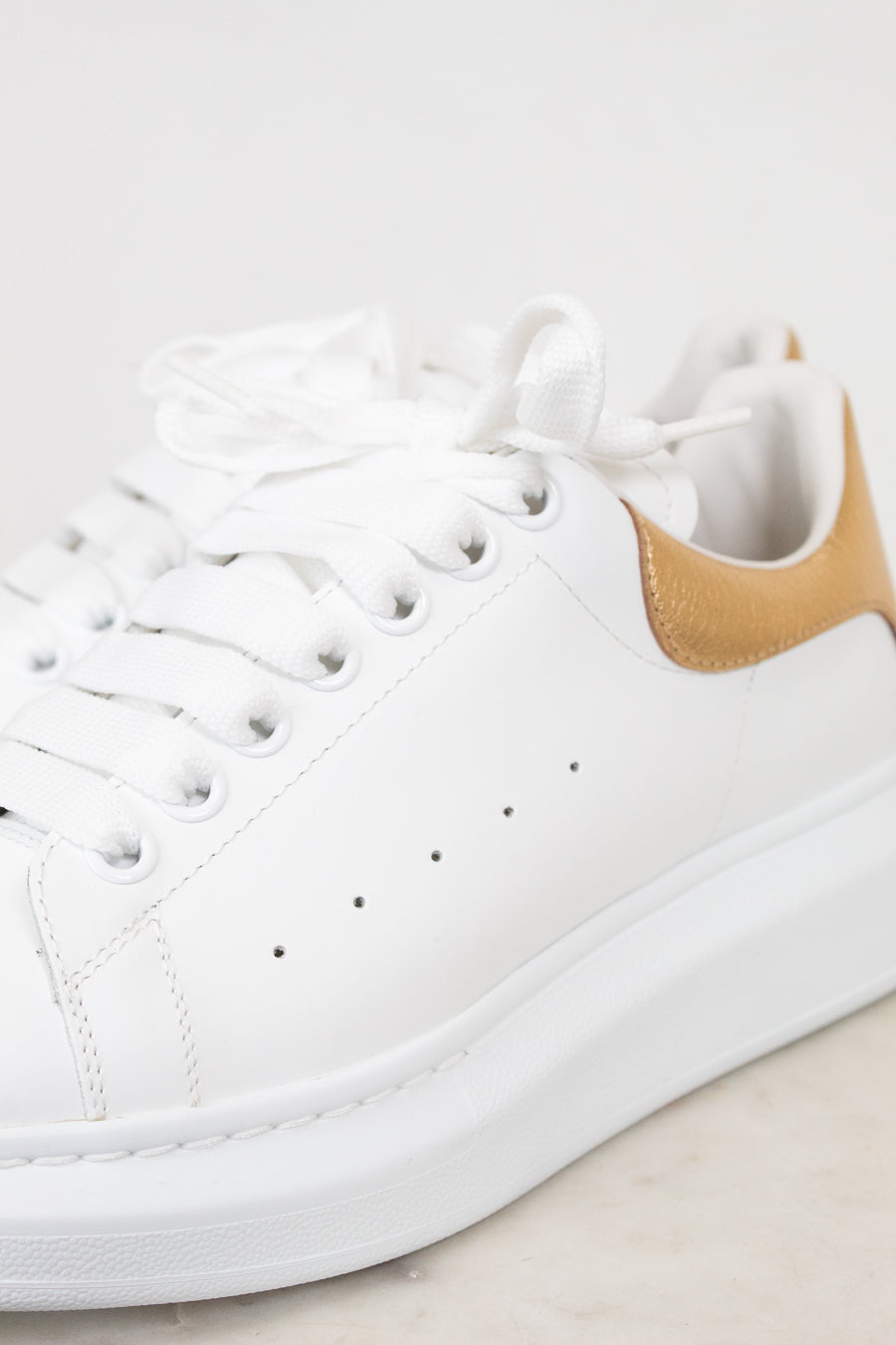 White sneaker with a gold accent on a light background