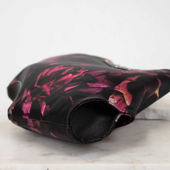 Black and pink floral-patterned purse on a white surface