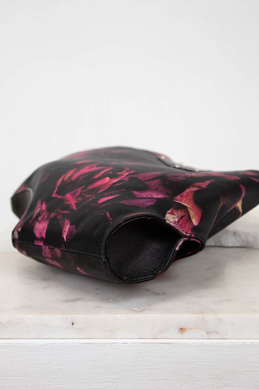 Black and pink floral-patterned purse on a white surface