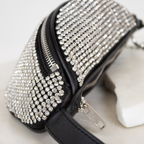 Black handbag with silver rhinestone embellishments on a marble surface