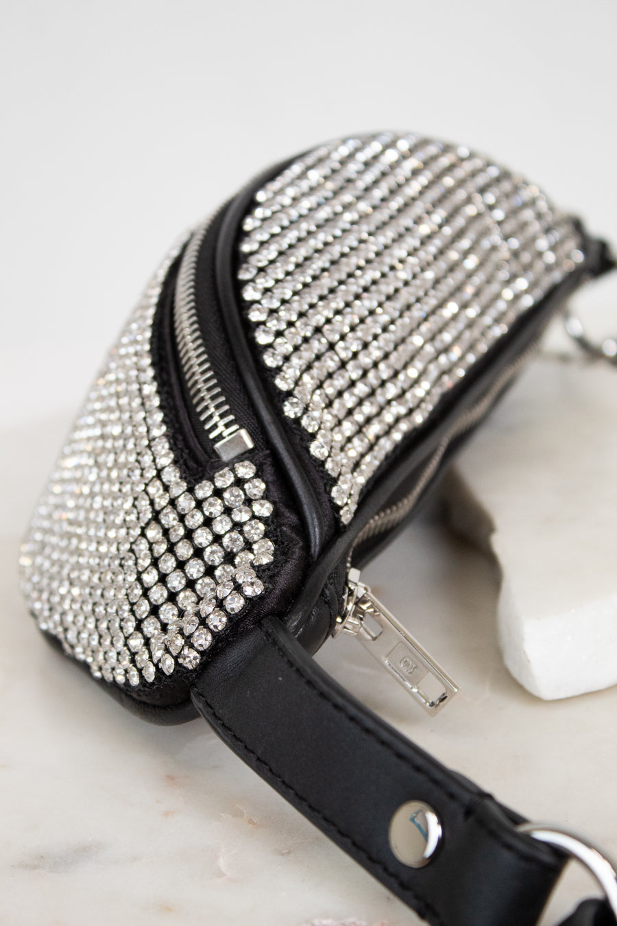 Black handbag with silver rhinestone embellishments on a marble surface