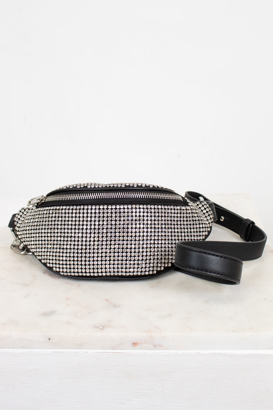 Black and silver studded checkered fanny pack on a light marble surface