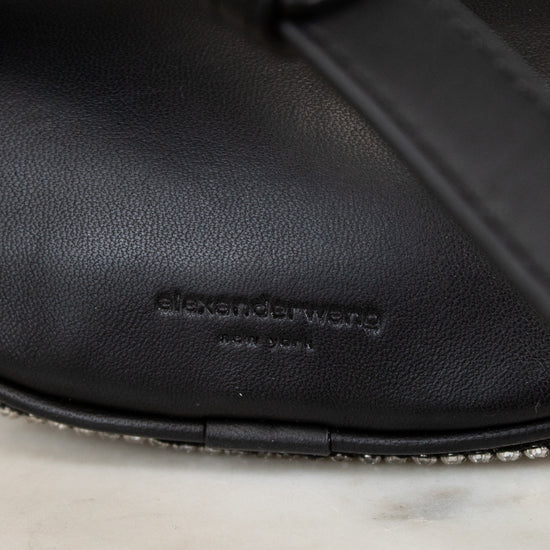 Black leather handbag on marble surface, featuring the Alexander Wang logo.
