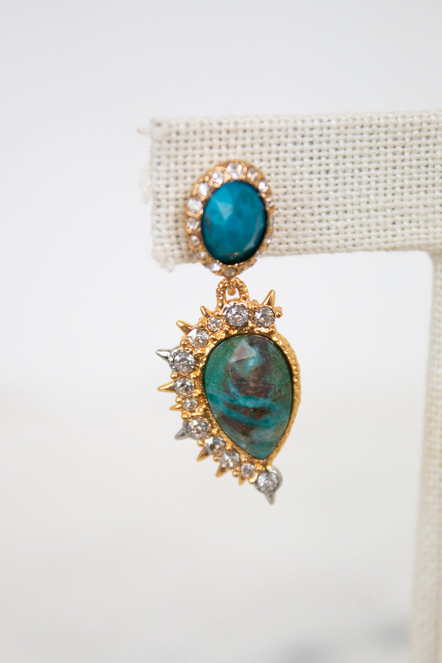 Gold earrings with turquoise stones on a white background