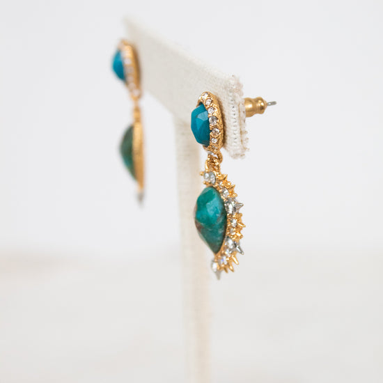 Pair of earrings with turquoise stones and gold accents on a white background
