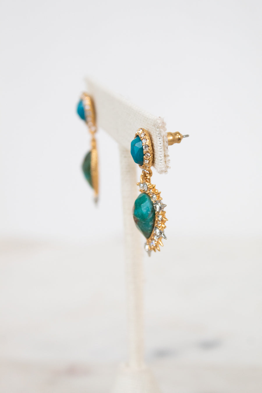Pair of earrings with turquoise stones and gold accents on a white background