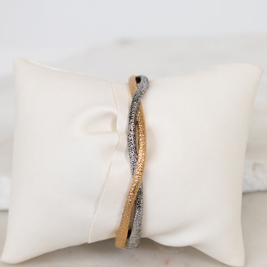 Two-tone bracelet on a white pillow with a marble surface