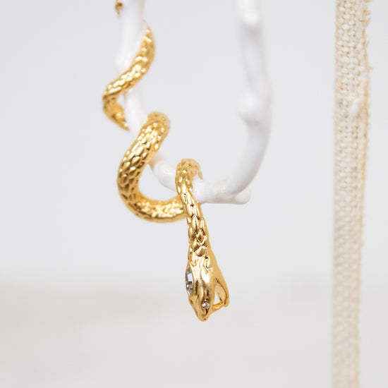 Gold snake-shaped earring on a white background