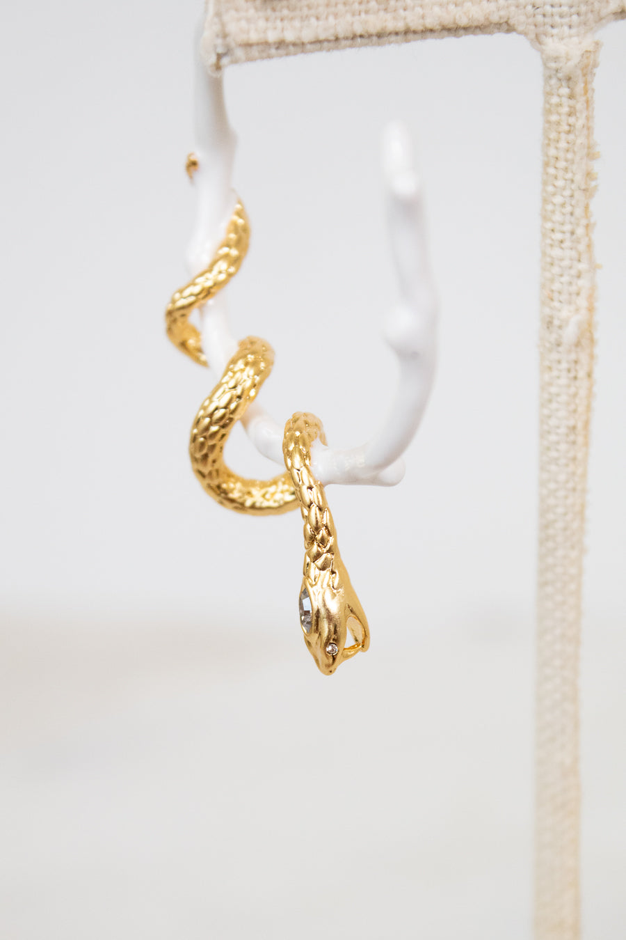 Gold snake-shaped earring on a white background