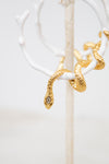 White hoop earring with gold snake details on a white stand with a white background