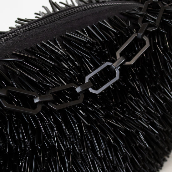 Black textured clutch bag with chain detail on a white background