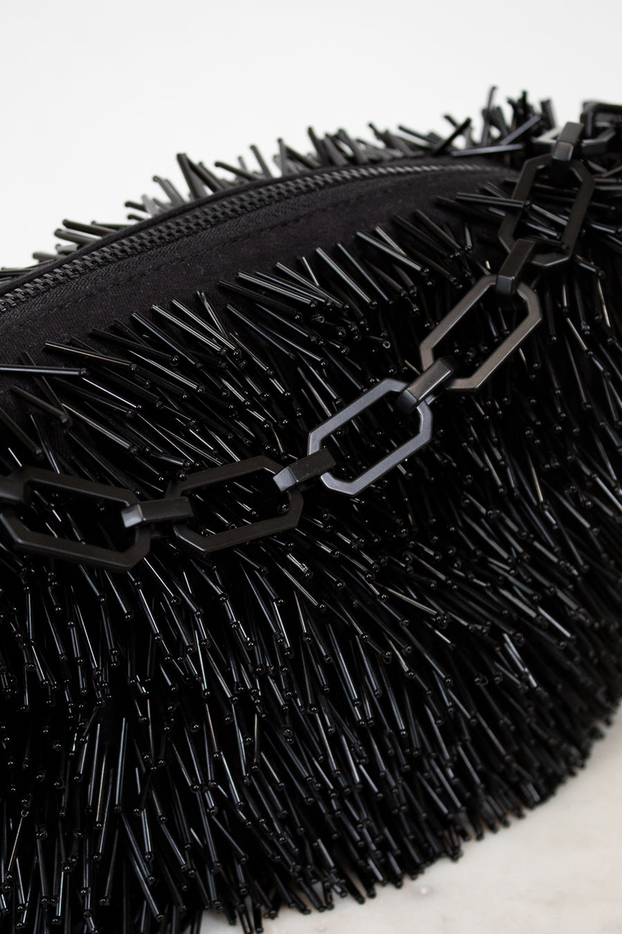 Black textured clutch bag with chain detail on a white background