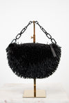 Black beaded handbag on a stand with a white background