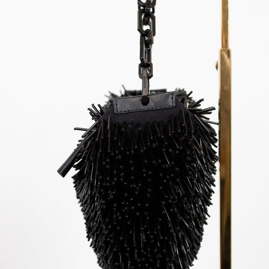 Black spiked bag hanging from a hook on a white background