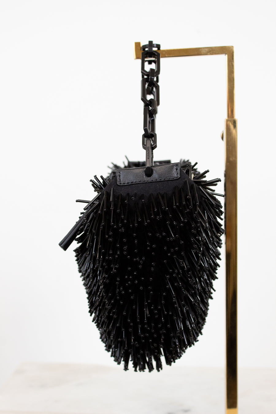 Black spiked bag hanging from a hook on a white background
