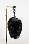Black beaded purse on a chain with a metal handle against a white background