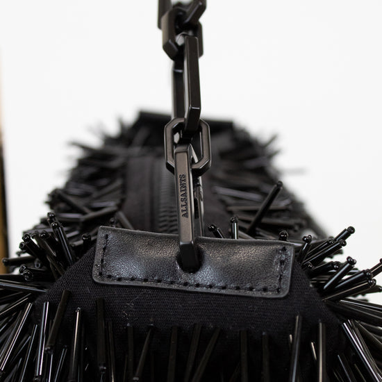 Black spiked handbag with a chain detail on a white background